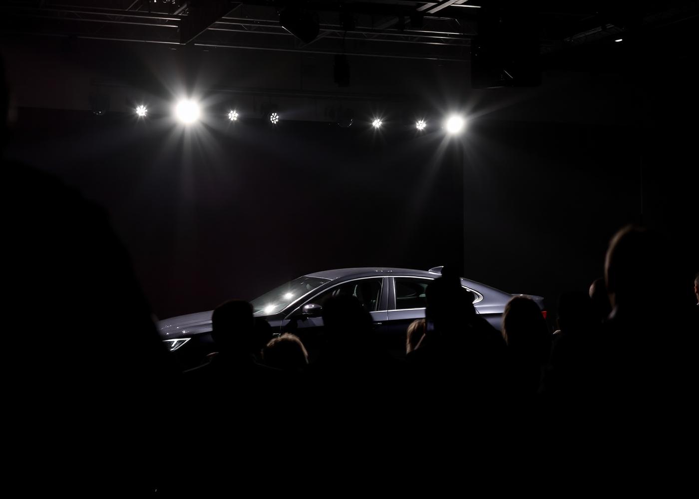 Bil under spotlights til et presseevent med publikum i silhuet